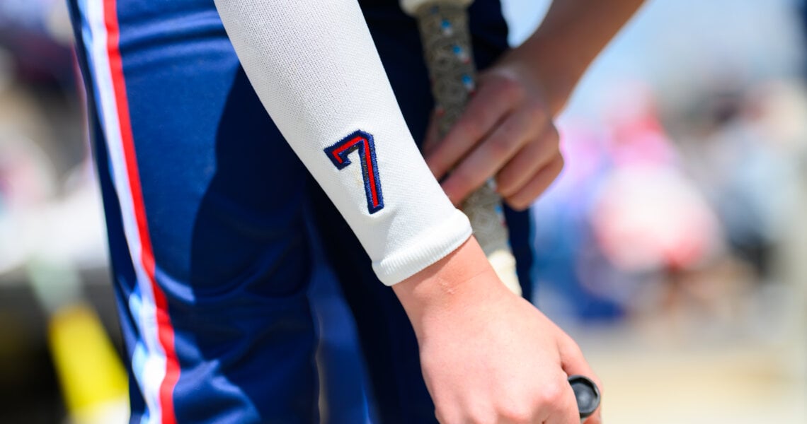 custom numbered arm sleeve shown on a baseball player who is holding a bat